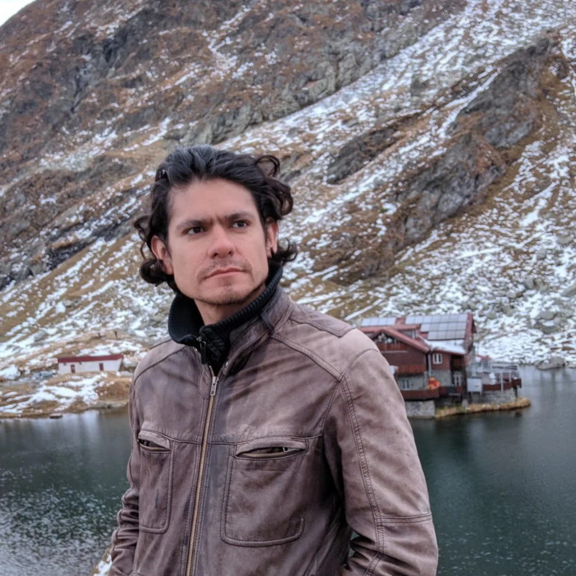 Juan Carlos Gomez standing in front of a majestic mountain in Romania.